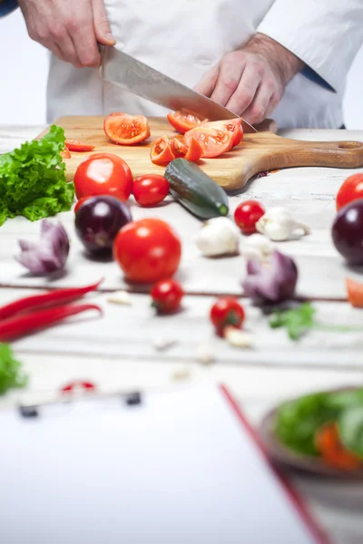 Chef tagliare un pomodoro rosso la sua cucina — Foto Stock