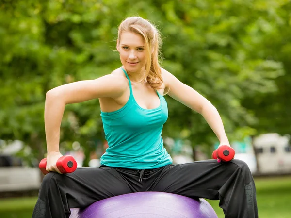 Sport meisje oefening met halters in het park — Stockfoto