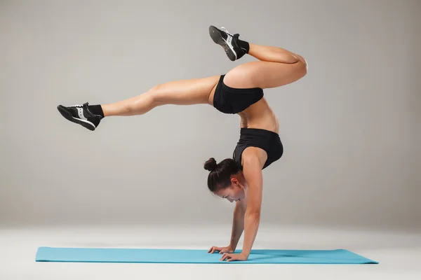 Krásná sportovní dívka stojící v Acrobatu pozice nebo jóga asana — Stock fotografie