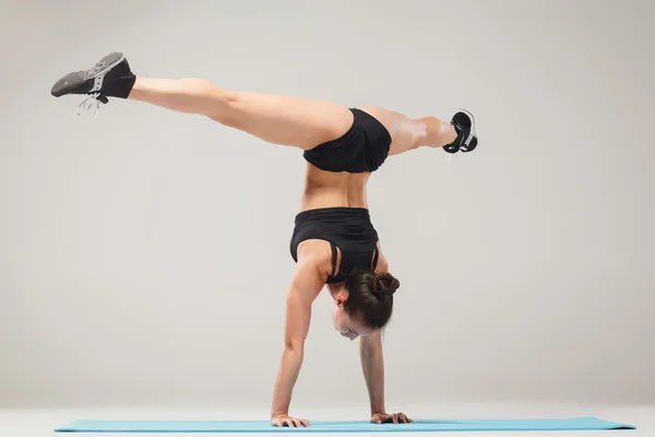 Hermosa chica deportiva de pie en pose acróbata o yoga asana —  Fotos de Stock