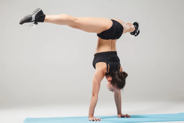 Hermosa chica deportiva de pie en pose acróbata o yoga asana —  Fotos de Stock