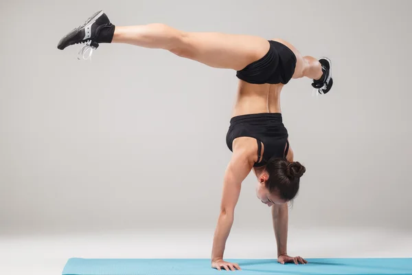 Beautiful sporty girl standing in acrobat pose or yoga asana — Stock Photo, Image