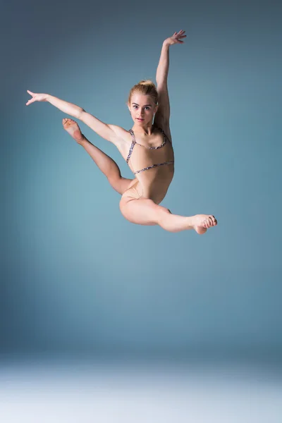 Giovane bella ballerina in stile moderno che salta su uno sfondo da studio — Foto Stock