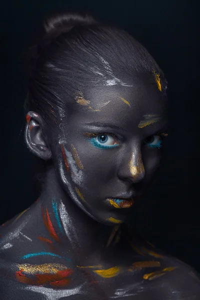 Portrait of a young woman who is posing covered with  black paint