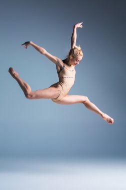 genç güzel modern stil dansçı bir stüdyo arka plan üzerinde atlama