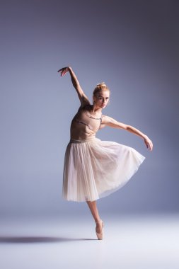 Stüdyo arka planında poz veren genç, güzel modern bir dansçı.