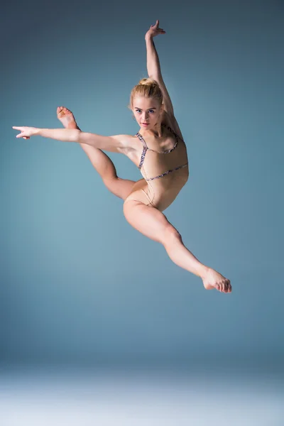Молодая красивая танцовщица в современном стиле, прыгающая на фоне студии — стоковое фото