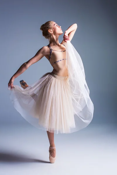 Jonge mooie ballerina danseres dansen op een studio achtergrond — Stockfoto