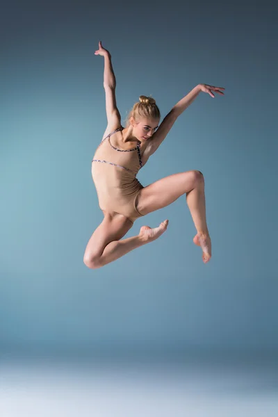 Jonge mooie moderne stijl danser springen op een studio achtergrond — Stockfoto