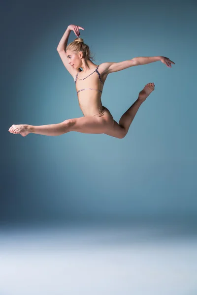 Giovane bella ballerina in stile moderno che salta su uno sfondo da studio — Foto Stock