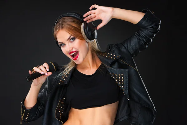 Retrato de una hermosa mujer cantando en el micrófono con auriculares —  Fotos de Stock