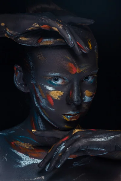 Portrait of a young woman who is posing covered with  black paint