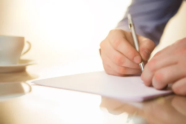 De mannelijke hand met een pen en de cup — Stockfoto