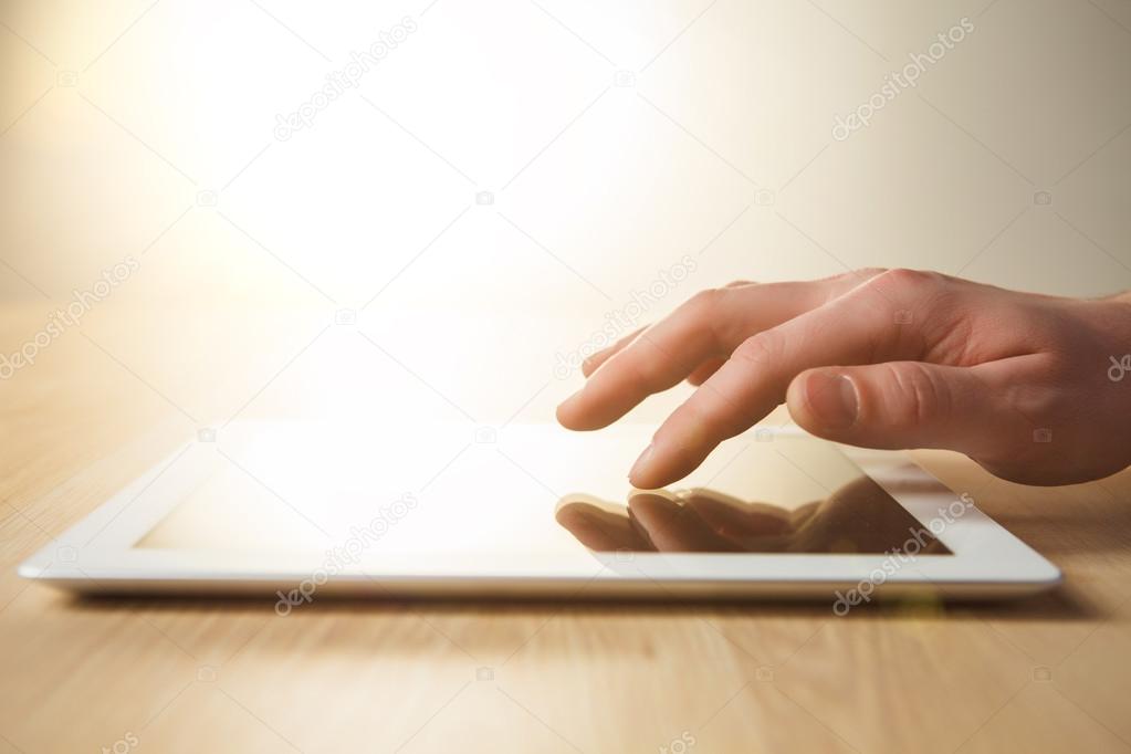 The tablet with the hand on wooden table