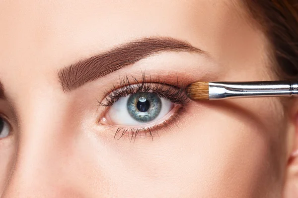 Beautiful female eyes with bright blue make-up and brush — Stock Photo, Image