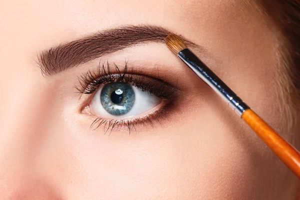 Mooie vrouwelijke ogen met helder blauwe make-up en borstel — Stockfoto