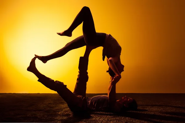 Two people practicing yoga in the sunset light — Stock Photo, Image