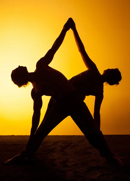 Duas pessoas praticando ioga na luz do pôr do sol — Fotografia de Stock