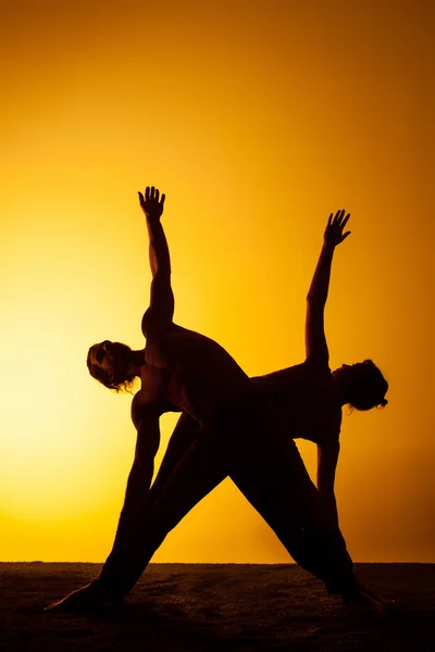 Duas pessoas praticando ioga na luz do pôr do sol — Fotografia de Stock