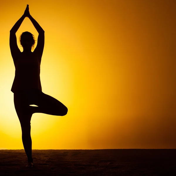 A mulher praticando ioga na luz do pôr do sol — Fotografia de Stock