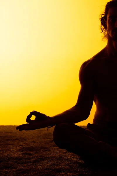Человек, практикующий йогу в лучах заката — стоковое фото
