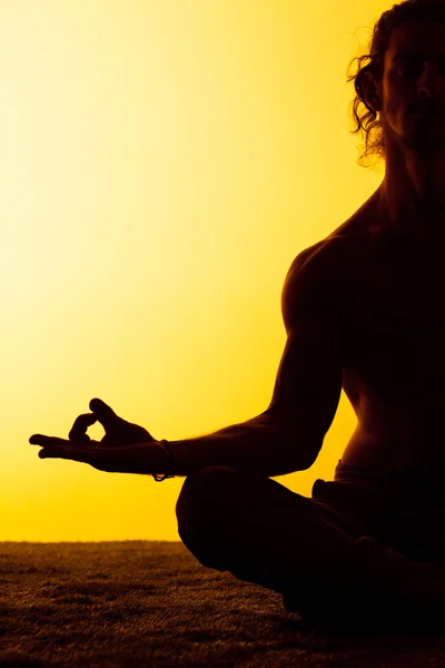 Человек, практикующий йогу в лучах заката — стоковое фото