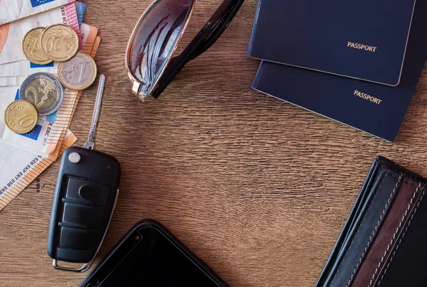 Travel concept. Smartphone, money, car key, passports, sunglasses and wallet on wooden background with copy space