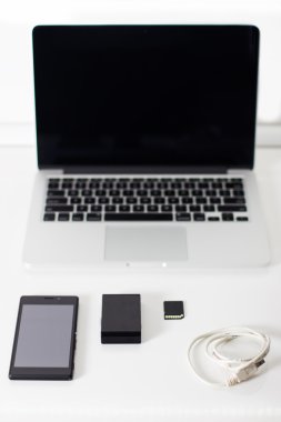 Siyah smartphone, bellek kartı ve fare ile açık dizüstü.