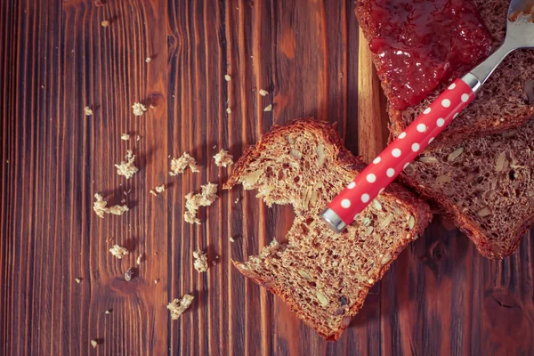 ขนมปังโฮลเทลกับแยมแอปริคอท ล้อมรอบด้วยผลไม้แห้ง . — ภาพถ่ายสต็อก
