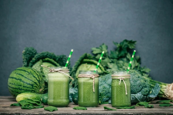 Blended green smoothie with ingredients on wooden table — Stock Photo, Image