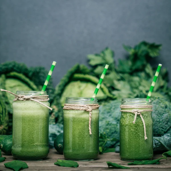 Blended green smoothie with ingredients on wooden table — Stock Photo, Image