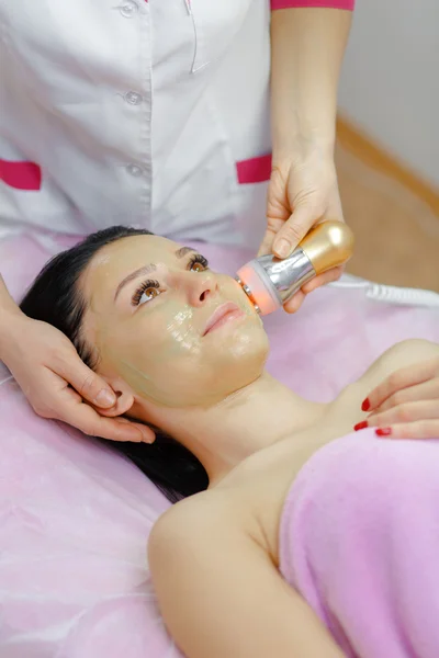 Young beautiful woman with dark hair gets procedure in the beauty salon — Stock Photo, Image