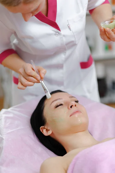 Young beautiful woman with dark hair gets procedure in the beauty salon — Stock Photo, Image