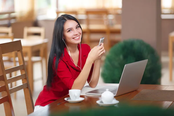 Giovane donna con telefono e laptop seduta nel caffè — Foto Stock