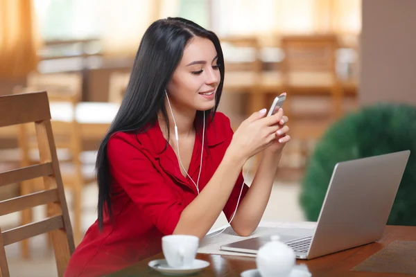 Jonge vrouw met telefoon en laptop zitten in het cafe — Stockfoto