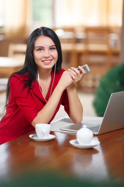 携帯電話、ノート パソコン、カフェに座っている若い女性 — ストック写真