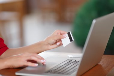 Kredi kartı tutan ve dizüstü bilgisayar kullanarak eller