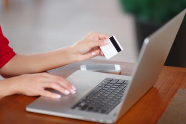 Kredi kartı tutan ve dizüstü bilgisayar kullanarak eller
