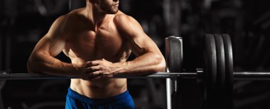 Çekici kaslı vücut geliştirmeci adam hazırlamak bir spor salonunda halter alıştırmalar yapmak