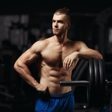 Çekici kaslı vücut geliştirmeci adam hazırlamak bir spor salonunda halter alıştırmalar yapmak