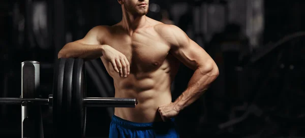 Attractive muscular bodybuilder guy prepare to do exercises with barbell in a gym — Stock Photo, Image