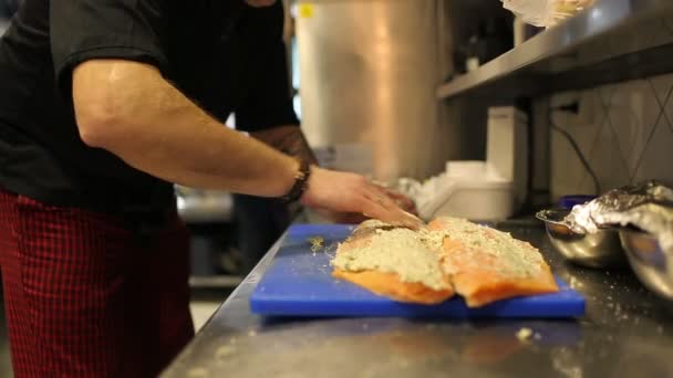 Mãos masculinas chef que lubrifica filé de peixe vermelho com molho branco — Vídeo de Stock