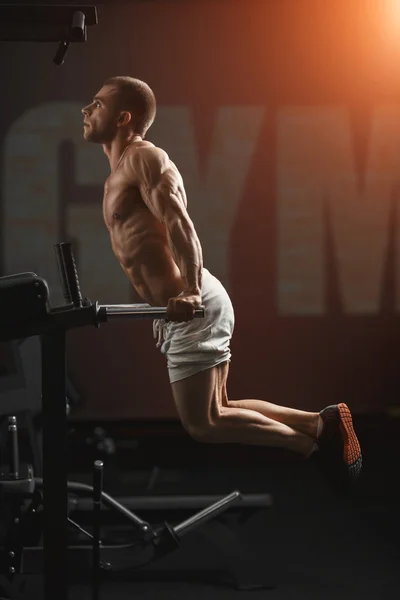 Strong bodybuilder doing exercise on bars — Stock Photo, Image