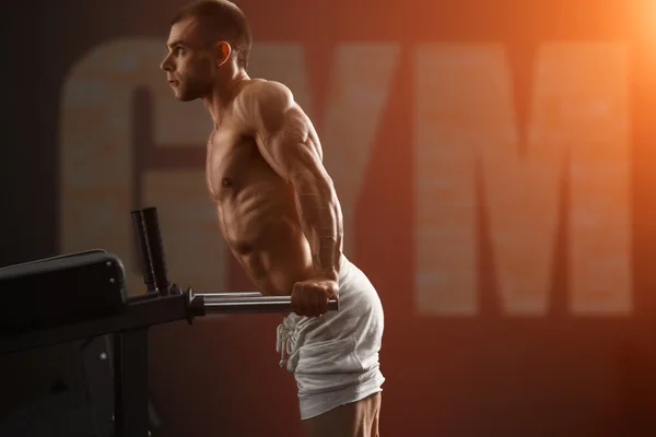 Strong bodybuilder doing exercise on bars — Stock Photo, Image