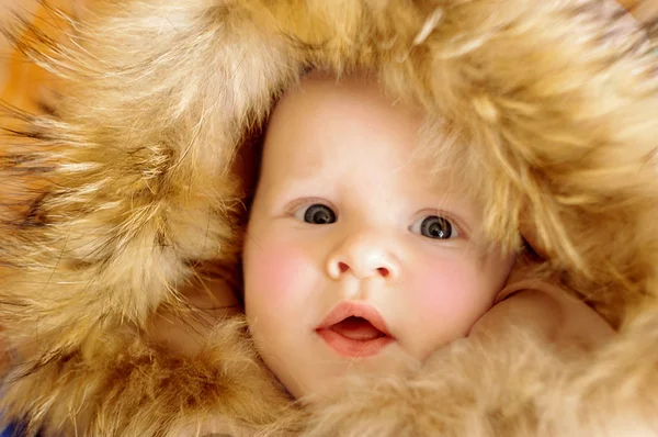 Baby mit Pelzmütze. wunderschönes Baby im Winterfell. — Stockfoto