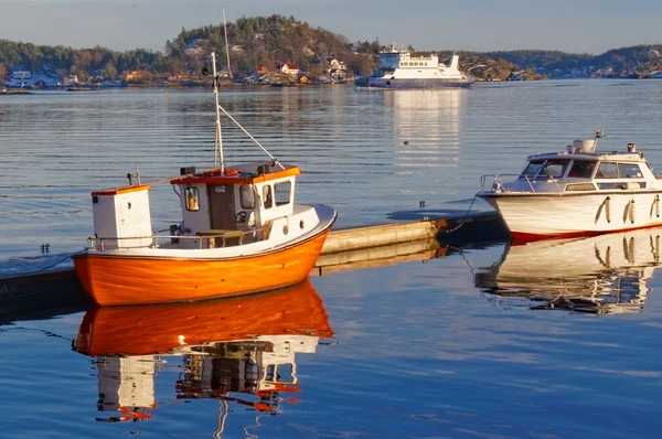 Pequeno barco de pesca laranja com reflexo na água — Fotografia de Stock