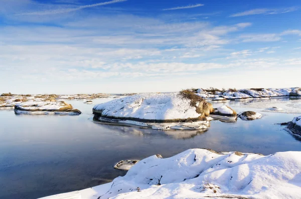 Kleine rotsachtige eilanden besprenkeld met sneeuw tijdens eb — Stockfoto