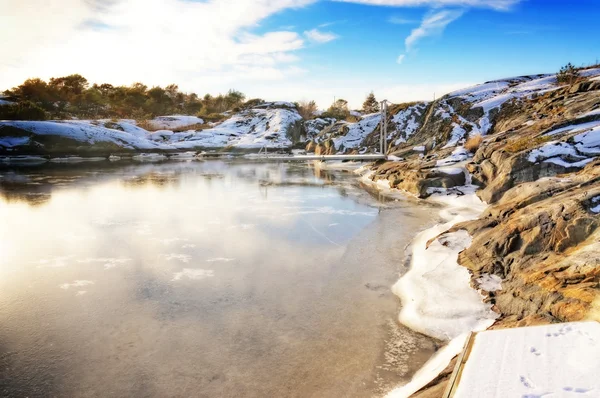 Baie avec quai entouré de côtes rocheuses en hiver — Photo