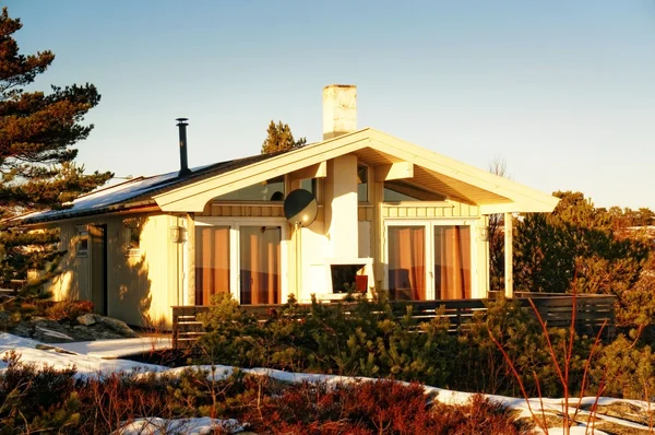 Large yellow cottage on rocks covered with snow — Stock Photo, Image