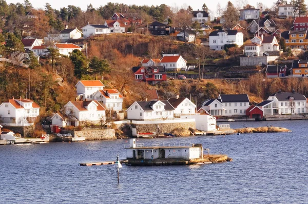 Skalnatý ostrov s budovami v fjordy, Norsko Stock Snímky